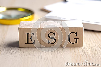 ESG on wooden cubes with magnifier and calculator, financial concept background Stock Photo