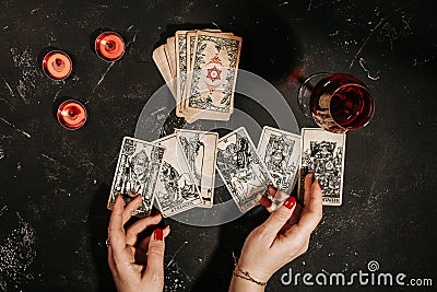 Tarot cards and female hands of fortune teller on black magic table Stock Photo