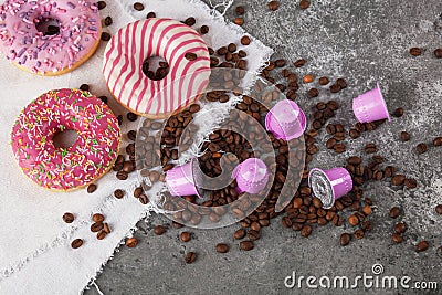 Espresso pink plastic capsules with foil and coffee beans and sweet donuts on gray concrete background Stock Photo
