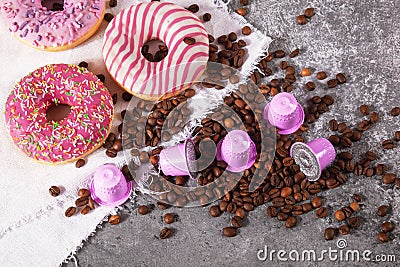 Espresso pink plastic capsules with foil and coffee beans and sweet donuts on gray concrete background Stock Photo