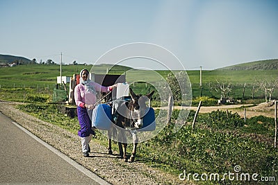 ESSAOUIRA, MOROCCO - JANUARY 17, 2020: Women with donkey walking down the street, wearing beautiful blue and white Arab clothes. Editorial Stock Photo
