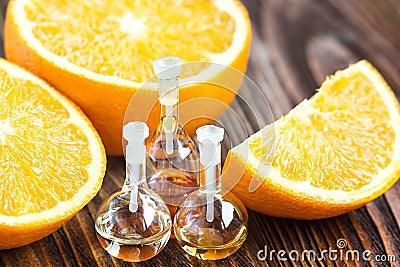 Essential aroma oil in glass bottle with fresh, juicy, ripe, orange fruit on wooden background. Beauty treatment. Spa concept. Sel Stock Photo