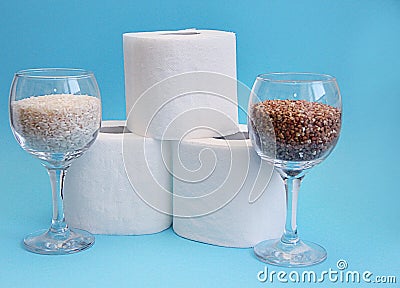 Essential goods for a coronovirus pandemic. rice and buckwheat are in a wine glass instead of wine and toilet paper rolls Stock Photo