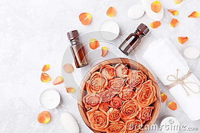 Essential oil bottle, rose flower in bowl, towel and candles on stone table top view. Spa, aromatherapy, wellness, beauty. Stock Photo