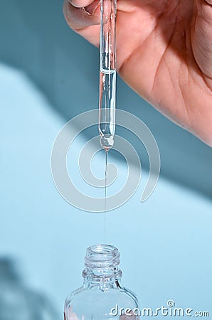 Essential oil dropping from pipette to the bottle. Essence liquid cosmetic. Syrup. Perfume.Aromatherapy Stock Photo