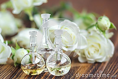 Essential oil in glass bottle with rose flowers on wooden background. Small bottles of perfume. Beauty treatment. Spa concept. Sel Stock Photo