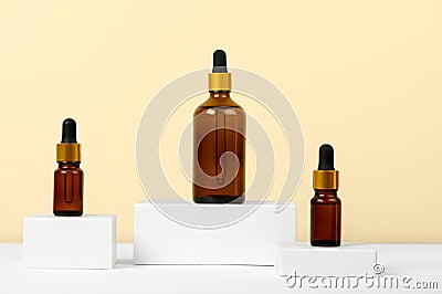 Essential oils on a beige background on white podiums, mockup. Cosmetic medical beauty product in brown glass bottles with a Stock Photo