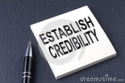 ESTABLISH CREDIBILITY text on the sticker with pen on the black background Stock Photo