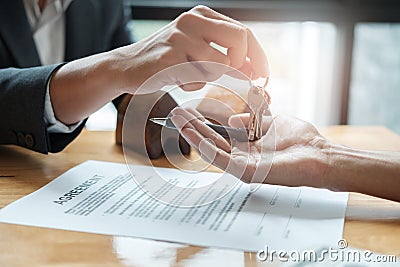estate agent giving house keys to man and sign agreement in office Stock Photo