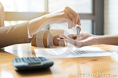 estate agent giving house keys to man and sign agreement in office Stock Photo