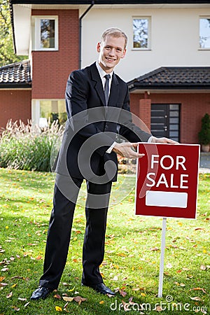 Estate agent holding sign outside Stock Photo