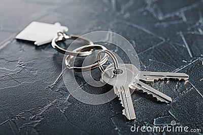 Estate concept with key, keychain with house symbol, stone background Stock Photo