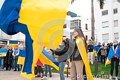 Anti-war demonstration. Women hold huge Ukrainian flags. Editorial Stock Photo