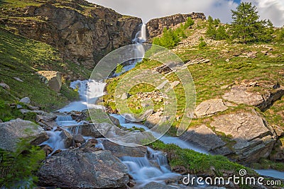 Ethereal waterfall and alpine meadows at springtime, Gran Paradiso Alps, Italy Stock Photo