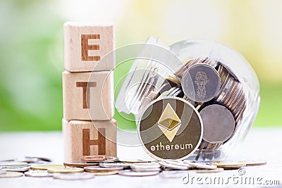 Ethereum ETH Coins and Wood block word ETH on blurred greenery background. Editorial Stock Photo