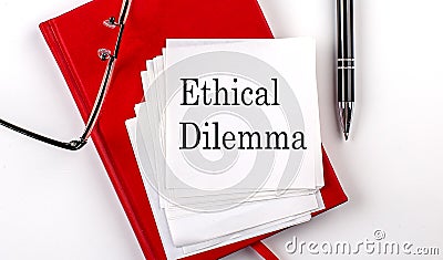 ETHICAL DILEMMA text on sticker on red notebook with pen and glasses Stock Photo