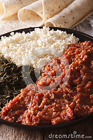Ethiopian kitfo with herbs and cheese ayibe and injera close-up. Vertical Stock Photo