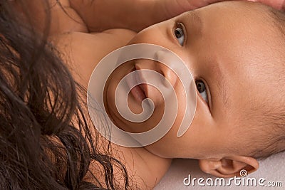 Ethnic biracial baby boy lying down by mother Stock Photo