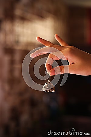 The Ethnic jhumka Indian traditional ear rings in girls hand Stock Photo