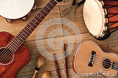 Ethnic musical instruments set: tambourine, wooden drum, brushes, wooden sticks, maracas and guitars laying on wooden Stock Photo