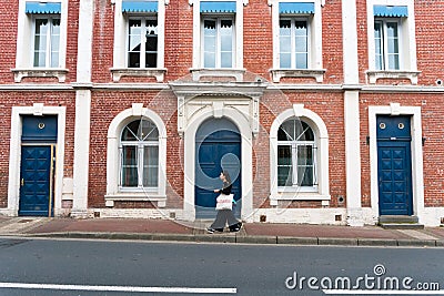 Typical Norman stone and brick house front with colorful contrasts and an Asian woman walking past Editorial Stock Photo