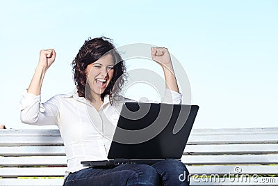 Euphoric businesswoman with a laptop sitting on a bench Stock Photo