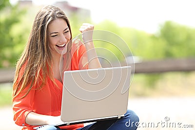 Euphoric woman searching job with a laptop in a park Stock Photo