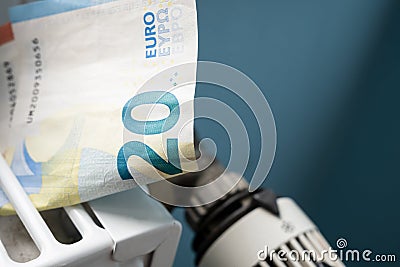 Euro banknotes in a radiator and a thermostat knob at a minimum, close-up. Concept of energy crisis and expensive Stock Photo