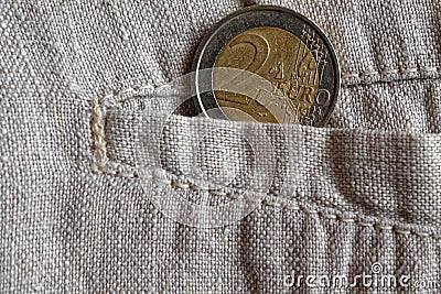 Euro coin with a denomination of 2 euros in the pocket of worn linen pants Stock Photo