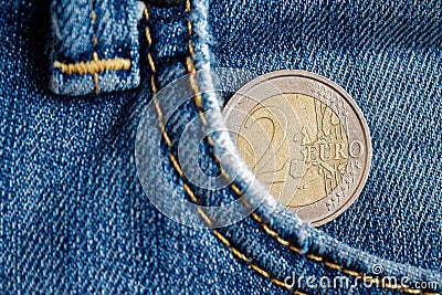 Euro coin with a denomination of two euro in the pocket of vintage worn blue denim jeans Stock Photo