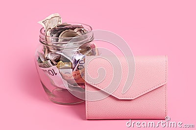 Euro and dollar banknotes in glass money jar with blank label and pink wallet, financial, saving.Moneybox with empty sticky note Stock Photo