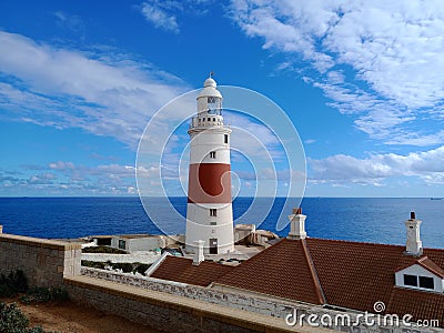 Europa Point Lighthouse with the sea and a cloudy blue sky in the background in Gibraltar Stock Photo