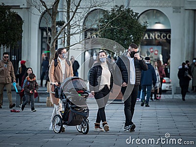 European Family, a father and mother, and their baby, in a stroller, walking wearing face mask protective equipement on covid Editorial Stock Photo