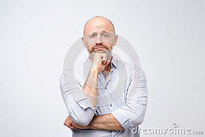 European man looking sadly at camera. Handsome mature adult with beard lost his job and thinking about future life. Stock Photo