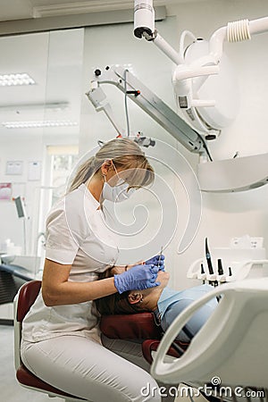 European mid pleased dentist woman in face mask working in dental clinic. Stock Photo