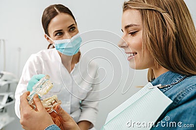 European pleased dentist woman showing teeth imitation to her patient Stock Photo