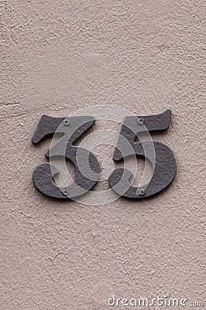 Number 35 vintage metal house number on gray wall Stock Photo