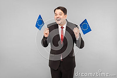 European politician holds flags and toothy smiling Stock Photo