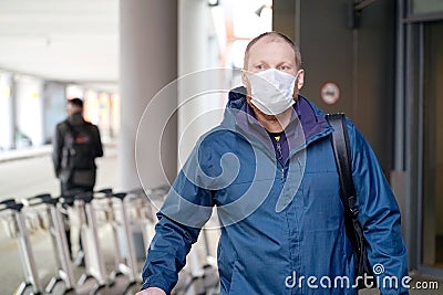 European redbeard man is in protective medical mask in airport Editorial Stock Photo