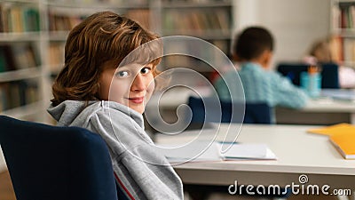 European schoolboy turning back, smiling at camera in class Stock Photo