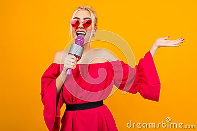 European sexy girl in a red dress with bare shoulders sings with a microphone in the studio Stock Photo