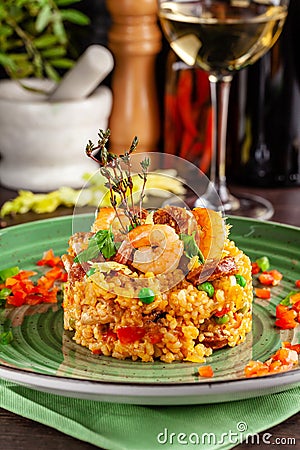 European Spanish cuisine. Paella with shrimps, chicken and coblas chorizo. White wine on the table. Closeup background image Stock Photo