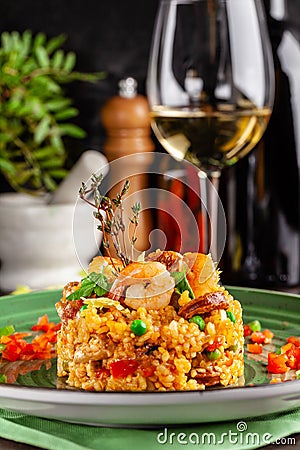 European Spanish cuisine. Paella with shrimps, chicken and coblas chorizo. White wine on the table. Closeup background image Stock Photo