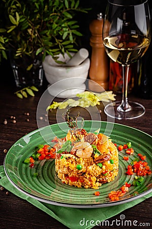 European Spanish cuisine. Paella with shrimps, chicken and coblas chorizo. White wine on the table. Closeup background image Stock Photo