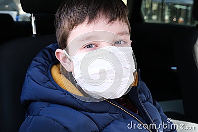 A european teen caucasian boy in car wearing white surgical medical face mask as a protection against virus disease Stock Photo