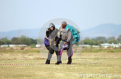 European white male walking and talking with black African skydiver after successful landings Editorial Stock Photo