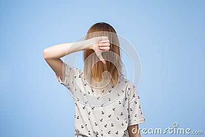 European woman shows disapproval sign, gives thumb down gesture, dislikes something, has disgusting expression Stock Photo