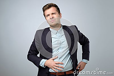 European young man in suit having stomach pain. Colic or flatulence Stock Photo