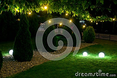 Evening illumination backyard light garden with electric ground sphere lantern. Stock Photo