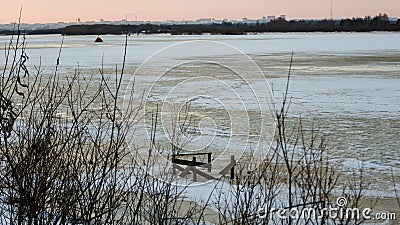 Evening landscape by the river in winter begins to melt the ice, over the horizon you can see the city Stock Photo